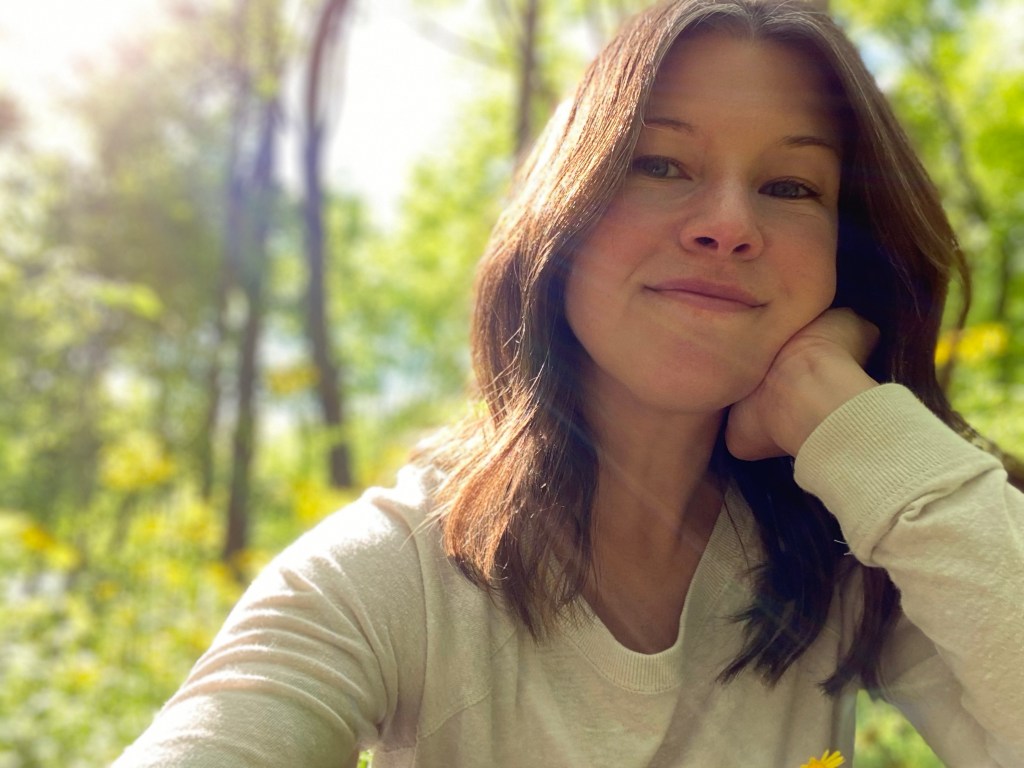 Photo of a white woman with brown hair in the woods